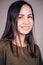 Close-up portrait of a young attractive brunette woman with clean healthy face skin looking with a smile at the camera. Happiness,