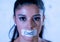 Close up portrait of young attractive latin woman with mouth sealed on stick tape with text no food in diet Anorexia eating