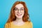 Close up Portrait young beautiful attractive redhair girl with eyeglass shocking with something. Blue Pastel Background