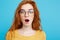 Close up Portrait young beautiful attractive redhair girl with eyeglass shocking with something. Blue Pastel Background