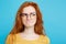 Close up Portrait young beautiful attractive redhair girl with eyeglass worry with something. Blue Pastel Background
