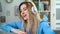 Close-up portrait of young beautiful girl in blue outfit enjoying the music at home. Woman listening music in headphones