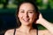 Close up portrait of a young beautiful smiling happy brunette girl in outdoor Park on a Sunny summer day correcting hand loose