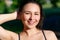 Close up portrait of a young beautiful smiling happy brunette girl in outdoor Park on a Sunny summer day correcting hand loose