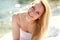 Close-up portrait young blond woman resting happily on sea beach