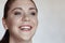 Close up portrait of young brunette woman with blue eyes widely laughing.