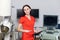 Close up portrait of young caucasian woman doctor in red uniform, holding digital tablet pc, posing near modern