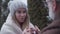 Close-up portrait of young charming Caucasian woman talking with senior husband outdoors. Pretty loving girl in winter