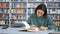 Close-up portrait of a young cheerful female student, she is looking for the necessary information in a book and writes