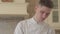 Close up portrait of young concentrated cook in chef uniform preparing food at home in the kitchen. Concept of food