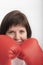 Close-up portrait of young dark-haired woman in red wrestling gloves. Woman boxer. Vertical frame. White background