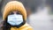 Close-up portrait young europeans woman in protective disposable medical face mask walking outdoors. New coronavirus COVID-19