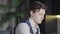 Close-up portrait of young focused brunette man working in atelier in the evening. Serious concentrated Caucasian tailor