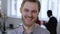 Close-up portrait of young happy European finance businessman cheerfully smiling at camera in modern office workplace.