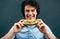 Close-up portrait of young happy man eating a healthy hamburger. Handsome man in a fast food restaurant eating a hamburger