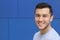 Close up portrait of a young hispanic teenager man looking at camera with a joyful smiling expression, against a blue background