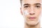 Close-up portrait of a young man with cosmetic cream on his face. Teenage guy cares about the cleanliness of the skin