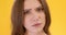 Close up portrait of young puzzled lady shaking head no and looking at camera with question, orange studio background