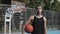 Close Up Portrait of Young Slim Fit Caucasian Basketball Player in Black Singlet Holding Ball Standing at Street