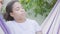 Close-up portrait of young smiling African American woman sitting in the hammock, relaxing in the garden, texting on