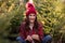 Close-up portrait of young woman with bright sparkler in hand among green pine Christmas trees