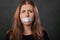 Close-up portrait of a young woman with duct tape sealed in her mouth, restriction of freedom of speech and censored