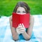 Close up portrait of young woman hiding his face behind book