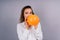 Close up portrait of a young woman inflating balloon on isolated grey background