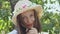 Close-up portrait of a young woman looking at camera in the park. Beautiful caucasian girl in straw hat. Leisure