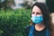 Close-up portrait of young woman in protective medical mask on her face, looking at camera outdoor.