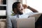 Close up positive African American man dreaming, relaxing with laptop