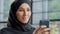 Close-up positive arab woman in hijab holding phone making order in online store friendly smiling muslim female