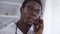 Close-up positive confident doctor in eyeglasses talking on phone smiling. Portrait of African American young man