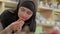 Close-up of positive confident Muslim woman choosing strawberry in grocery. Portrait of beautiful girl in hijab
