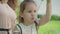 Close-up of positive little girl blowing soap bubbles as unrecognizable mother clapping hands at the background. Happy