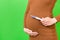 Close up of positive pregnancy test against pregnant woman`s belly at green background. Future mother in brown dress. Baby