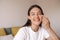 Close- up positive young cucasian woman in white t-shirt applying face cream with finger.