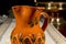 Close-up of pottery jug to serve wine or water on an embroidered table mat