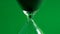 Close up pouring black sand in an hourglass standing an green background 4k