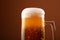 Close up pouring frothy beer in glass over brown