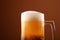 Close up pouring frothy beer in glass over brown
