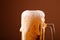 Close up pouring frothy beer in glass over brown