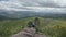 Close up POV of hiking boots of an independent male traveler on top of a mountain, looking at the view.