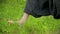 Close-up of a practicing man`s legs outdoors in the grass. Crossing bare feet in qigong exercises. The concept of a