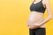 Close up of pregnancy bandage dressed on pregnant woman for reducing backpain at yellow background with copy space. Orthopedic