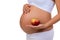 Close-up of pregnant belly and apple. Vitamins and healthy food during pregnancy