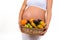 Close-up of a pregnant belly and a basket of exotic fruits.