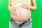 Close up of pregnant belly at colorful background with copy space. Future mother in opened jeans is embracing her naked baby bump