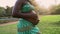 Close up pregnant belly of young African woman in park during sunset time