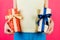 Close up of pregnant woman in colorful home clothing holding two gift boxes at pink background. Is it a boy or a girl Expecting